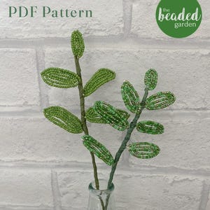 Może przedstawiać: Wzór PDF na gałązkę z zielonych koralików, z tekstem "PDF Pattern" i "the beaded garden" na obrazku.