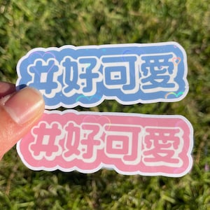 May include: Two stickers with the Chinese characters "好可爱" (hǎo kě'ài) which means "so cute" in English. The stickers are in a bubble font and are pink and blue.