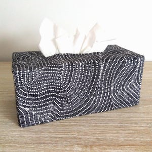 May include: Black and white tissue box cover with a wavy, dotted pattern.