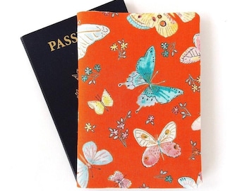 Funda para pasaporte con diseño de mariposa, ideal para viajeros con doble nacionalidad: fondo naranja y rojo.