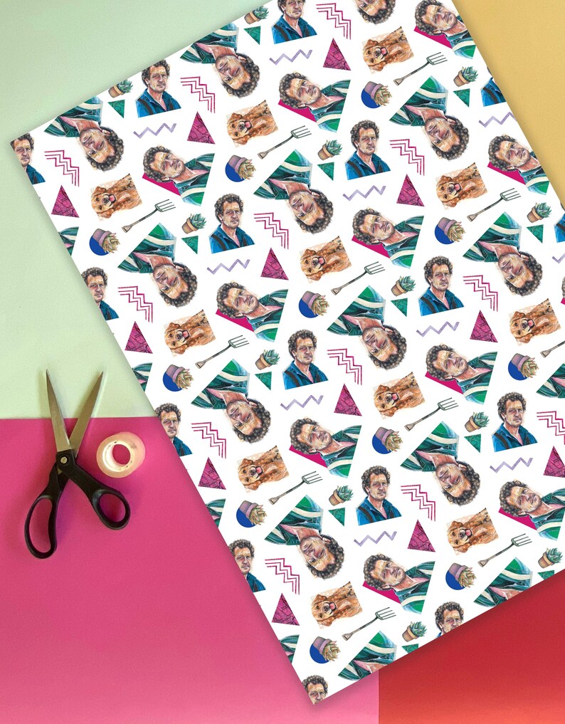 May include: White wrapping paper with a repeating pattern of a man's portrait, a dog, a gardening fork, a potted succulent, and geometric shapes in pink, green, and blue. A pair of black scissors and tape are on a pink and yellow background.