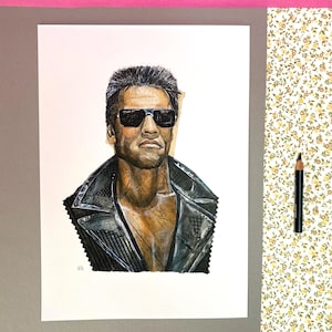 May include: A detailed watercolor portrait of a man wearing sunglasses and a black leather jacket. The artwork is on white paper, with a pink and gray background. A pencil rests on a floral patterned surface.