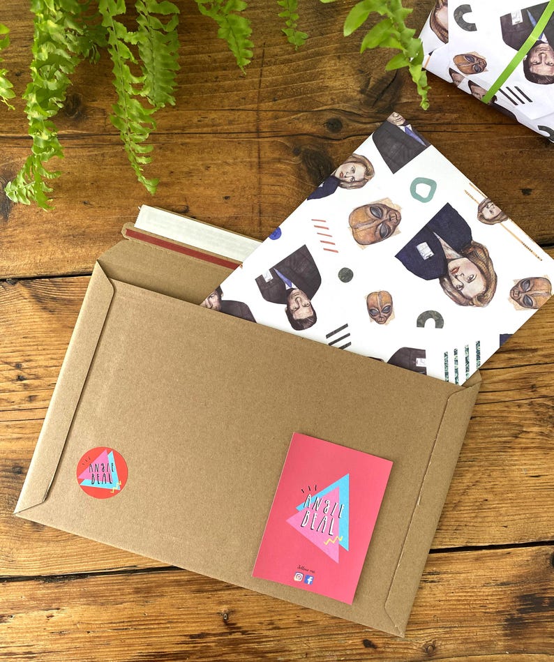 May include: A brown paper envelope with a white and blue patterned wrapping paper inside. The wrapping paper features a repeating pattern of faces and geometric shapes. The envelope has a red and white sticker with the text "an all deal" on it.
