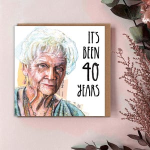 May include: A birthday card featuring a watercolour portrait of an elderly woman with white hair. The card reads "IT'S BEEN 40 YEARS" in black text. The card is on a brown background.