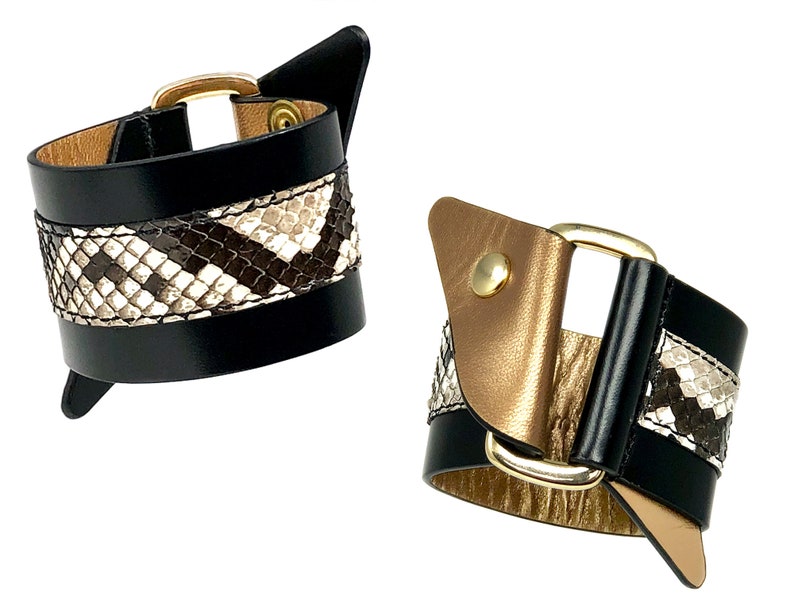 May include: Two black leather bracelets with gold buckles and a snakeskin pattern.
