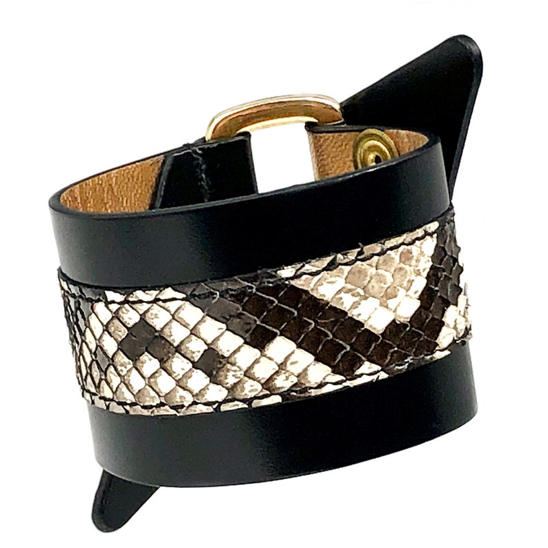 May include: Black leather bracelet with a snakeskin pattern and a gold buckle.