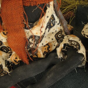 K&ouml;nnte beinhalten: Eine handgemachte Stoffpuppe mit einem Sackleinen-Schal und einem schwarz-wei&szlig;en Stoffkleid mit Halloween-Motiv. Die Puppe sitzt auf einer Sackleinen-Oberfl&auml;che.