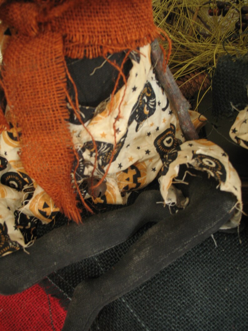 K&ouml;nnte beinhalten: Eine handgemachte Stoffpuppe mit einem Sackleinen-Schal und einem schwarz-wei&szlig;en Stoffkleid mit Halloween-Motiv. Die Puppe sitzt auf einer Sackleinen-Oberfl&auml;che.