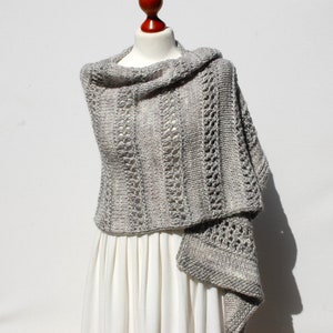 May include: A gray knitted shawl with a lacy pattern. The shawl is draped over a white dress form.