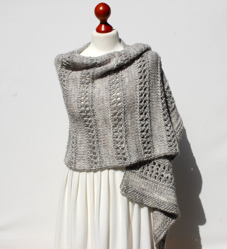 May include: A gray knitted shawl with a lacy pattern. The shawl is draped over a white dress form.