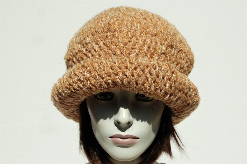 Puede incluir: Un gorro de punto marr&oacute;n y blanco con un ala ancha.