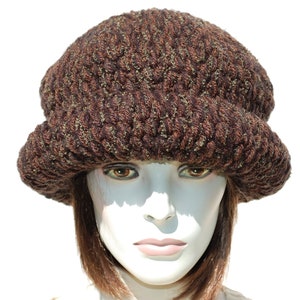 Puede incluir: Un gorro de punto marr&oacute;n y verde con un ala ancha. El gorro est&aacute; hecho de un hilo suave y texturizado y tiene un estilo &uacute;nico y holgado.