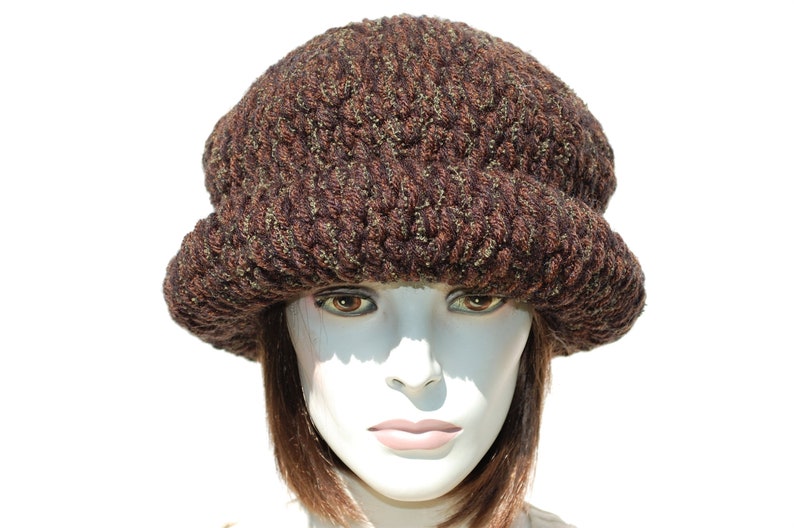 Puede incluir: Un gorro de punto marr&oacute;n y verde con un ala ancha. El gorro est&aacute; hecho de un hilo suave y texturizado y tiene un estilo &uacute;nico y holgado.