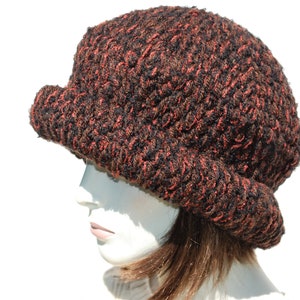 Puede incluir: Un gorro de punto marr&oacute;n y naranja con un ala ancha. El gorro est&aacute; hecho de un hilo suave y texturizado.