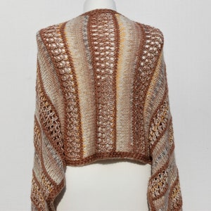 May include: A brown, white, and beige striped knitted sweater with a crocheted design. The sweater has a cropped length and long sleeves.