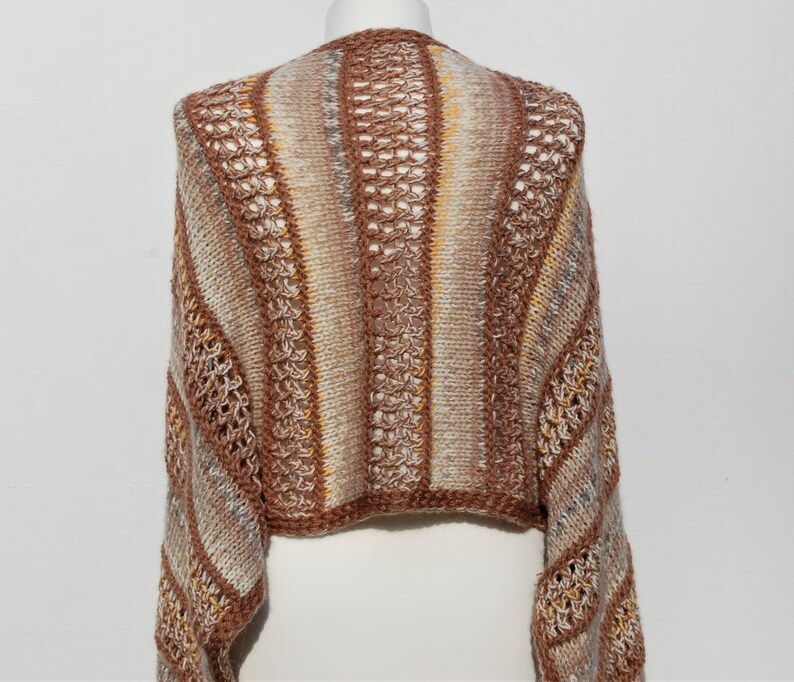 May include: A brown, white, and beige striped knitted sweater with a crocheted design. The sweater has a cropped length and long sleeves.