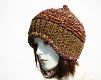 Puede incluir: Un gorro de punto marrón con un detalle de rayas multicolores. El gorro está hecho con un hilo grueso y tiene un ajuste holgado.