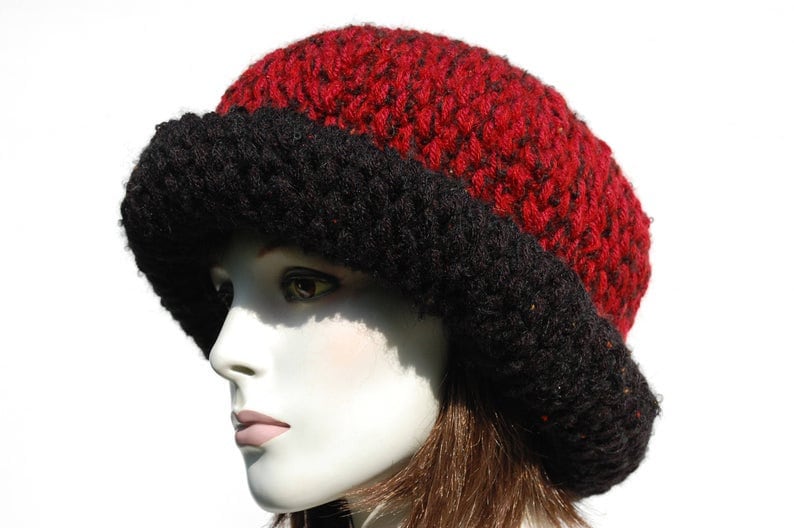 Puede incluir: Un gorro de punto rojo y negro con un ala ancha. El gorro est&aacute; hecho de un hilo suave y peludo.