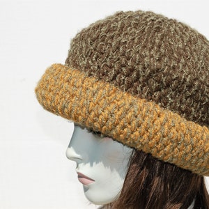 Puede incluir: Un gorro de punto marr&oacute;n y dorado con un dise&ntilde;o texturizado. El gorro est&aacute; hecho de un hilo suave y peludo.
