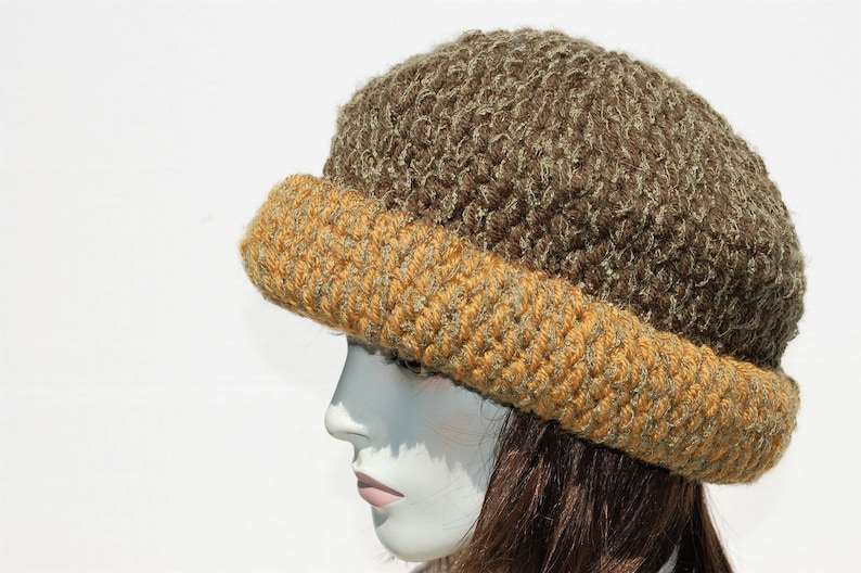 Puede incluir: Un gorro de punto marr&oacute;n y dorado con un dise&ntilde;o texturizado. El gorro est&aacute; hecho de un hilo suave y peludo.