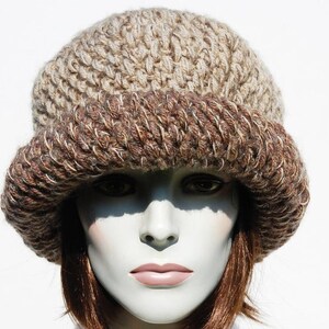 Puede incluir: Un gorro de punto de color marr&oacute;n y beige con un ala ancha. El gorro est&aacute; hecho de un hilo suave y texturizado y tiene un ajuste holgado.