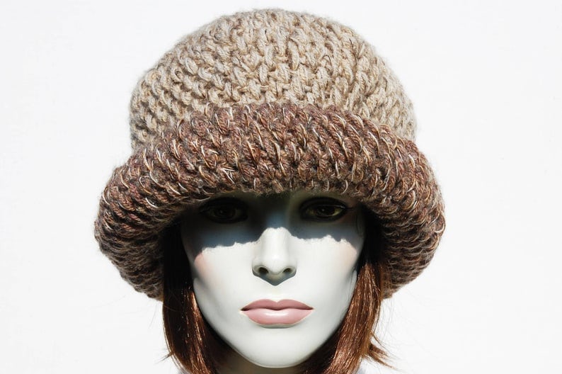 Puede incluir: Un gorro de punto de color marr&oacute;n y beige con un ala ancha. El gorro est&aacute; hecho de un hilo suave y texturizado y tiene un ajuste holgado.