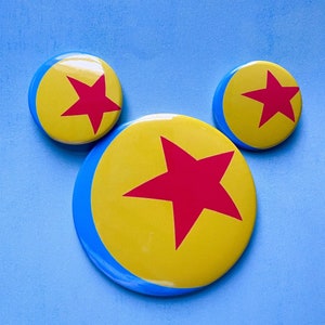 May include: Three yellow and blue round buttons with a red star in the center. The stars are different sizes and the buttons are arranged in a triangle shape.