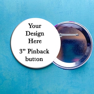 May include: A white 3" pinback button with the text "Your Design Here" and "3" Pinback button". The back of the button is silver with a pin.