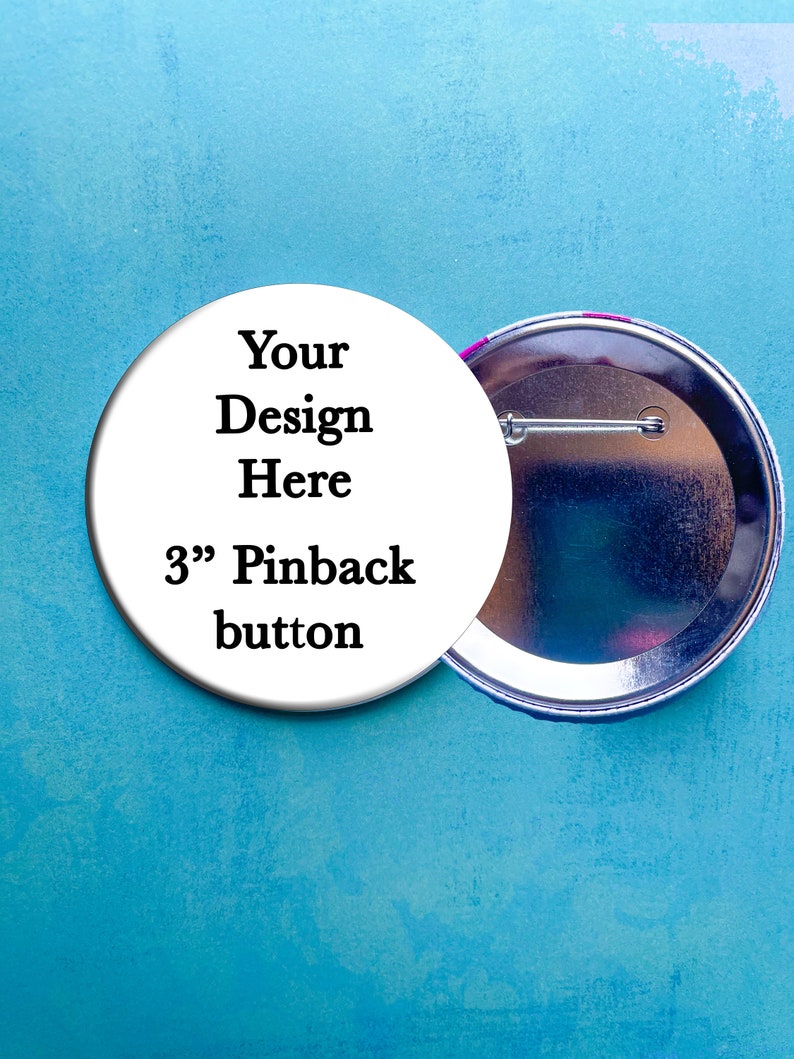 May include: A white 3" pinback button with the text "Your Design Here" and "3" Pinback button". The back of the button is silver with a pin.