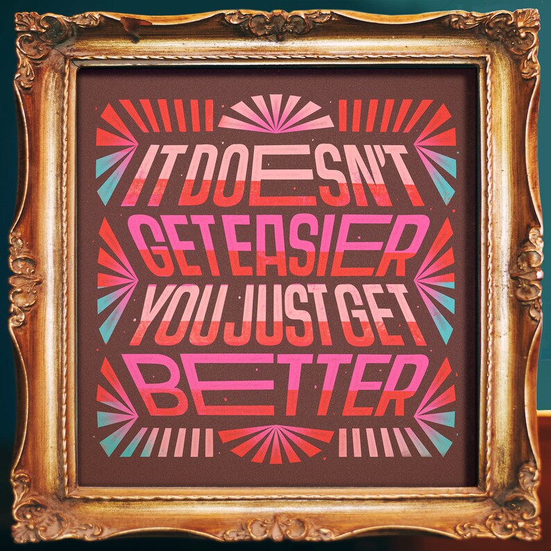 May include: A framed print with a motivational quote in a retro style. The quote reads "It doesn't get easier you just get better." The background is brown with pink, red, and blue accents.