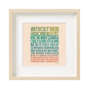 May include: A framed print featuring a light peach background with multi-coloured text that reads: WITHOUT NEW VISIONS WE DON'T KNOW WHAT TO BUILD, ONLY TO KNOCK DOWN. WE NOT ONLY END UP CONFUSED, RUDDERLESS AND CYNICAL BUT WE FORGET THAT MAKING A REVOLUTION IS NOT A SERIES OF CLEVER MANOEUVRES AND TACTICS BUT A PROCESS THAT CAN AND MUST TRANSFORM. -ROBIN D.G. KELLEY.