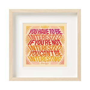 May include: A framed print with a yellow background and a quote in a colorful gradient font that reads "You have to be interested. If you're not interested you can't be interesting." The quote is attributed to Iris Apfel.