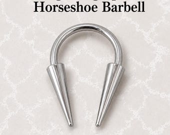 May include: A 14g long spike horseshoe barbell body jewelry piece made of polished silver-colored metal. The text 14g Long Spike Horseshoe Barbell is displayed above the item, with the Bessie's Body Jewellery logo positioned below it.