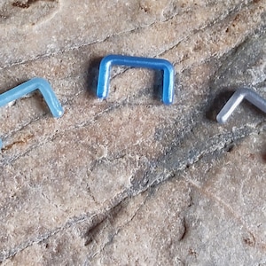 May include: Three different colored seamless hoop earrings. The hoops are made of a shiny metal and are in the colors blue, light blue, and silver.