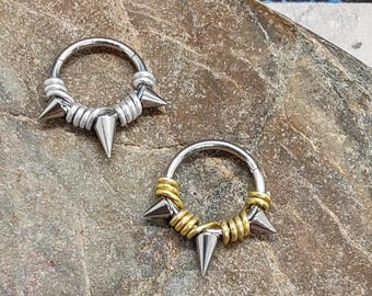 May include: Two silver and gold body jewellery rings with spikes. The rings are made of surgical steel and have a wire design. The spikes are pointed and sharp.