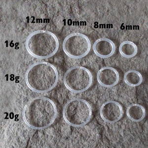 May include: A set of clear plastic hoop earrings in various sizes, ranging from 6mm to 12mm. The hoops are labeled with their diameter in millimeters and gauge in gauge sizes, 16g, 18g, and 20g.