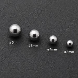 May include: Four polished silver-colored metal spheres arranged in a row from largest to smallest. The spheres are labeled with text indicating their sizes: #6mm, #5mm, #4mm, and #3mm, corresponding to each individual sphere from left to right.