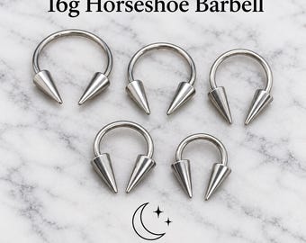 May include: Five silver-toned 16g horseshoe barbells with pointed cone ends. The text 16g Horseshoe Barbell is at the top, and the text Bessie's Body Jewellery with a crescent moon and star icon is at the bottom of the image.