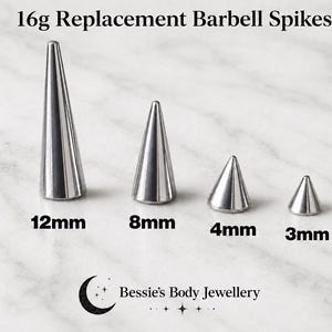 Puede incluir: Cuatro puntas de repuesto de metal plateado para barras de piercing en diferentes alturas etiquetadas como 12mm, 8mm, 4mm y 3mm. El texto 16g Replacement Barbell Spikes aparece arriba y el logo de Bessie's Body Jewellery abajo.