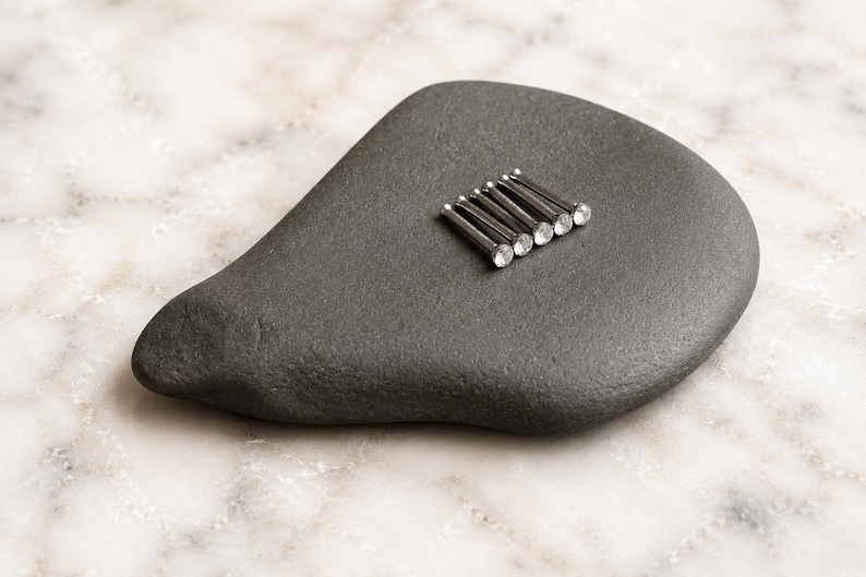 May include: Five silver-toned metal pins with clear, round, faceted crystal heads arranged in a parallel row. Each pin features a slender, straight shaft and a sparkling, circular stone setting at the top, creating a uniform and decorative appearance.