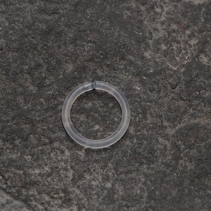 Può includere: Un anello di plastica trasparente, probabilmente utilizzato per l'artigianato o la creazione di gioielli.