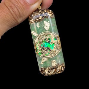 May include: A green and gold pendant with a geometric design and gold flakes. The pendant is made of resin and has a clear, glassy finish.