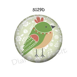 May include: A round, decorative button featuring a stylized bird design. The bird has a green body, tan belly, and red accents, set against a light green floral background. The text "S129D" is printed at the top.