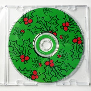 May include: A green CD with a holly and berry design. The text "CD-R" is printed on the disc.