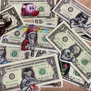 May include: A collection of colourful stickers featuring various characters and designs on a background of US dollar bills. The stickers include a pink cartoon character, a man in a Santa hat, a man in a baseball cap, and a man in a fast food uniform. The stickers are all labelled with the hashtag #BILLTHEWORM.