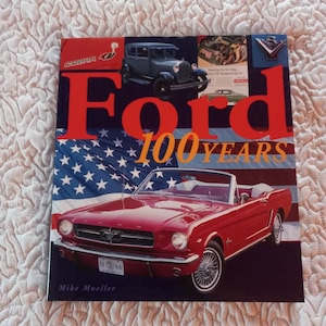May include: A red Ford Mustang convertible with a white American flag background. The car has a black license plate that reads "19 964". The book cover reads "Ford 100 Years" with the word "Ford" in red and "100 Years" in gold.