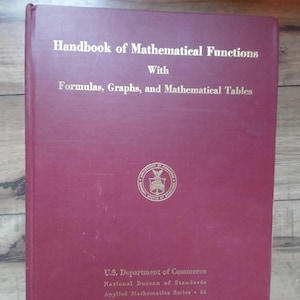 May include: A burgundy hardcover book titled "Handbook of Mathematical Functions" with "Formulas, Graphs, and Mathematical Tables" printed below the title. The book is published by the U.S. Department of Commerce, National Bureau of Standards, Applied Mathematics Series 55.