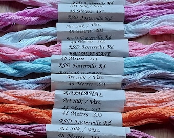 May include: A collection of 10 spools of embroidery floss in various colors, including green, pink, light blue, peach, orange, red, and purple. Each spool is labeled with the brand name "RSD Fosterville Rd" and "Bagshot East", the color number, and the material "Art Silk/Visc."