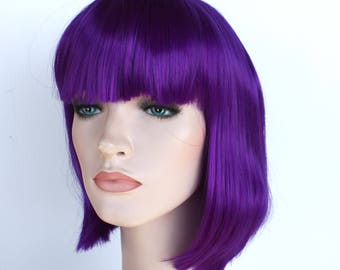 May include: A short, straight, purple wig with bangs. The wig is made of synthetic hair and is styled in a bob.