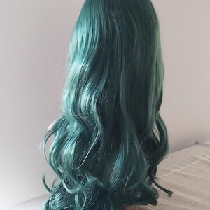 May include: A long, wavy, teal green wig on a mannequin head.